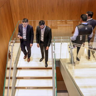 Four American Securities male employees in business attire walk chatting in an stairwell in a modern office